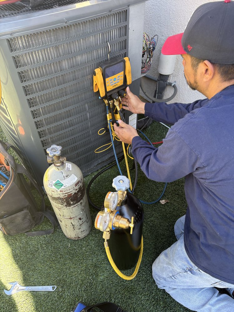 Technician diagnosing an AC unit with digital gauges